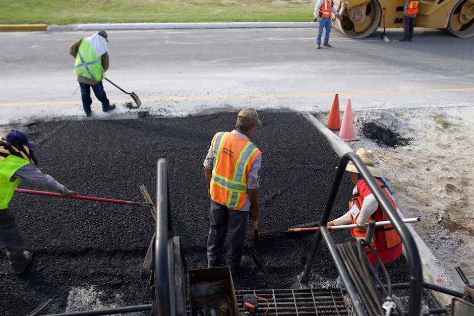 Group of road construction workers laying fresh asphalt outdoors during the day.